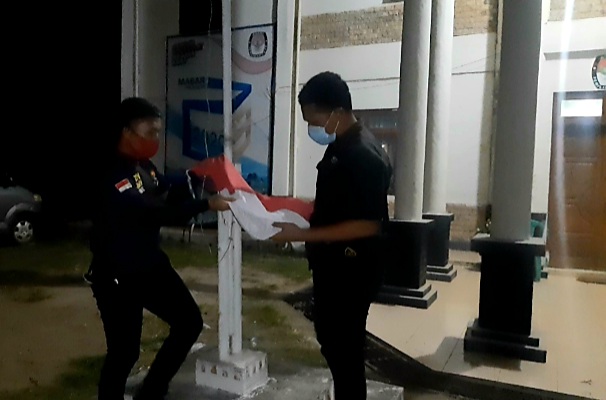 Dua orang jurnalis di Labuan Bajo turunkan bendera merah putih di Kantor KPU Mabar