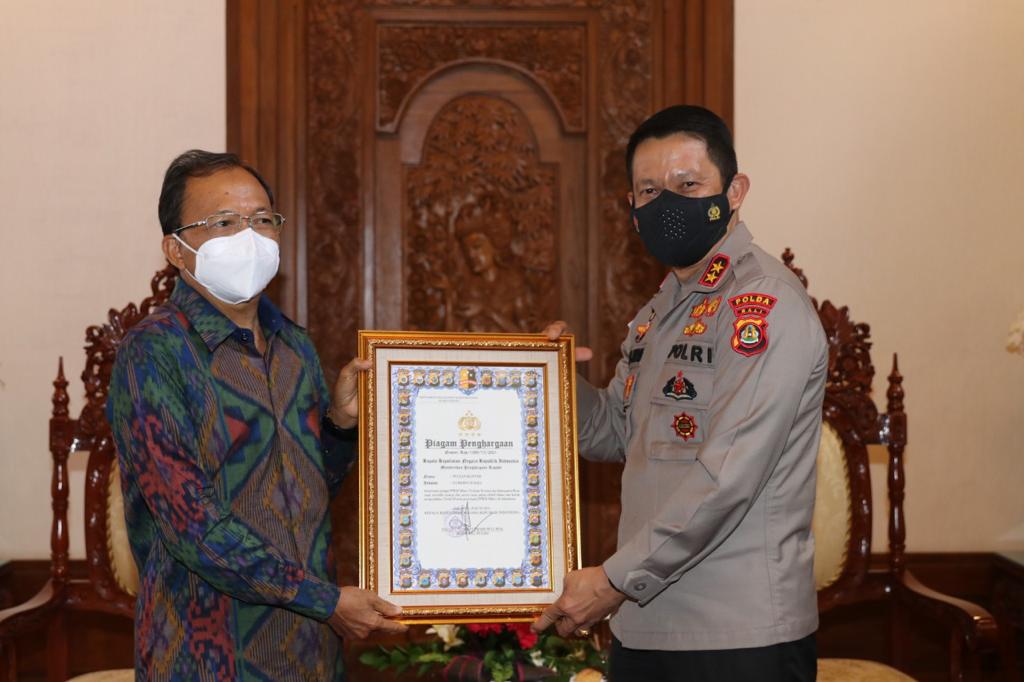 Kapolda Bali, Irjen Pol. Putu Jayan Danu Putra menyerahkan penghargaan dari Kapolri kepada Gubernur Bali, Wayan Koster.