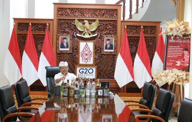 Gubernur Bali, Wayan Koster mengacungkan jempol untuk minuman arak Bali yang dipajang beberapa botol di meja kerjanya saat mengikuti pada Sidang Penetapan WBTb yang dilaksanakan secara hybrid (luring dan daring) pada tanggal 27 September hingga 1 Oktober 2021, di Hotel The Alana Malioboro, Yogyakarta. (FOTO/Hm)